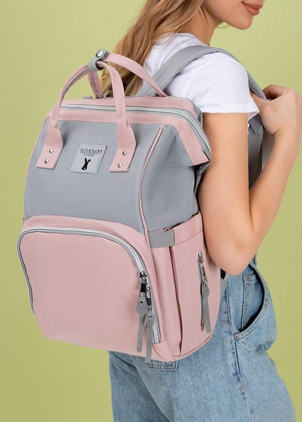 Сумка-рюкзак ILM Mammy bag для мам; серо-розовый (арт. 104326) Удобная и практичная сумка-рюкзак для современных мам с USB портом и ремнями для коляски. С этой сумкой Вам будет удобно и на каждодневной прогулке с ребенком, и в длительном путешествии.
Ткань рюкзака не промокает, поэтому вещи малыша останутся сухими в дождливую или снежную погоду. Даже пролитый сок не станет проблемой. За рюкзаком легко ухаживать – достаточно протереть его влажной салфеткой или постирать в машинке.
Габариты: 43х30х15 см. (высота*ширина*глубина), вместимость 15 л.
Преимущества сумки-рюкзака: 
• 3 термокармана для бутылочек (сохраняют тепло до 3х часов) 
• 2 водонепроницаемых кармана для мокрых вещей  
• Съемные двусторонние карабины для крепления на коляске
• Удобные крепкие ручки и мягкие лямки легко регулируются 
• Карман на спине открывает прямой доступ к вещам со дна
• Встроенный USB port для зарядки телефона и другой техники во время прогулки
• 11 глубоких карманов для любых целей
• Нержавеющая молния и карабины 
• Разработка США ORIGINAL DESIGN